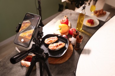 Photo of Shooting tasty roasted fish with smartphone in studio, above view. Professional food photography