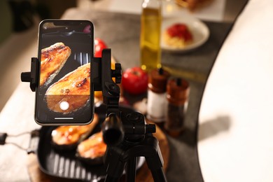 Photo of Shooting tasty roasted fish with smartphone in studio, above view. Professional food photography