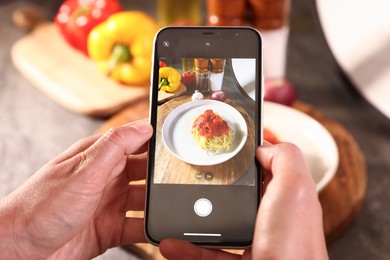 Photo of Woman taking picture of tasty pasta and ingredients in studio, selective focus. Professional food photography