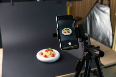Photo of Shooting tasty pasta with smartphone in studio, focus on screen. Professional food photography