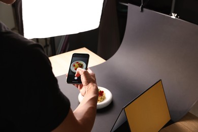 Photo of Man taking picture of pasta with smartphone in studio, closeup. Professional food photography