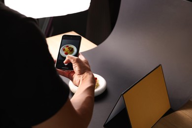 Photo of Man taking picture of pasta with smartphone in studio, closeup. Professional food photography