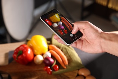 Photo of Woman taking picture of vegetables with smartphone in studio, closeup. Professional food photography