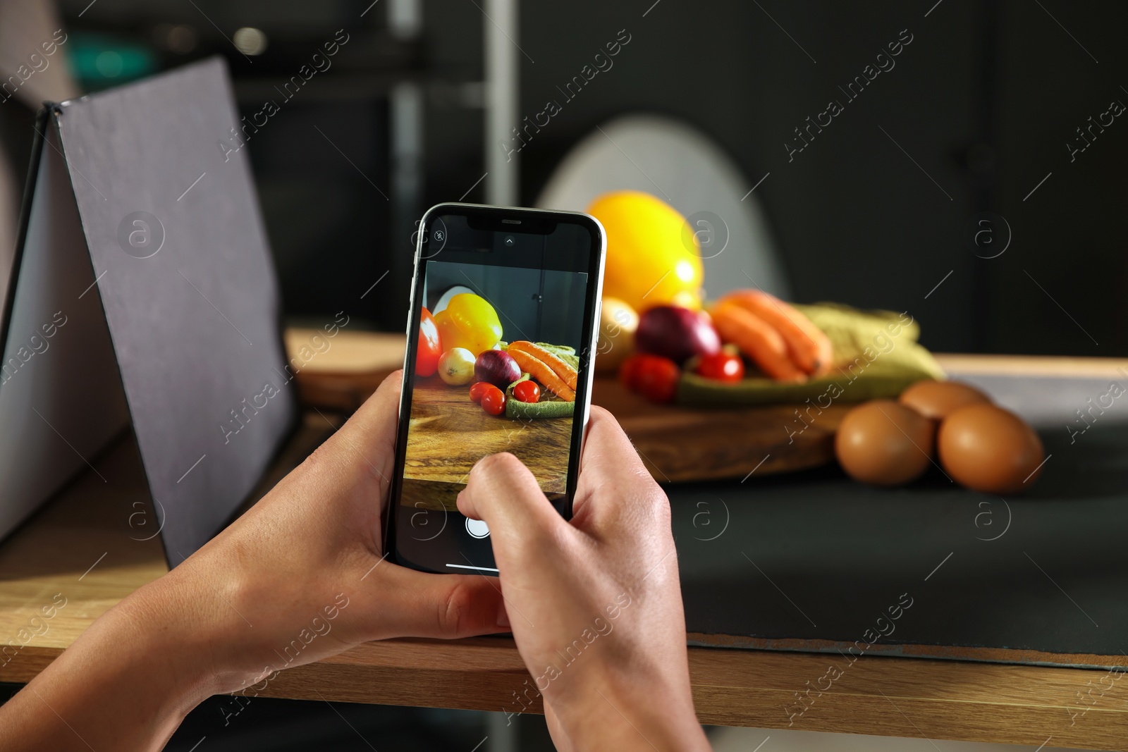 Photo of Woman taking picture of vegetables with smartphone in studio, closeup. Professional food photography