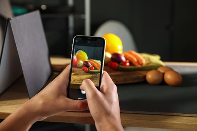 Photo of Woman taking picture of vegetables with smartphone in studio, closeup. Professional food photography