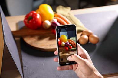 Photo of Woman taking picture of vegetables with smartphone in studio, closeup. Professional food photography