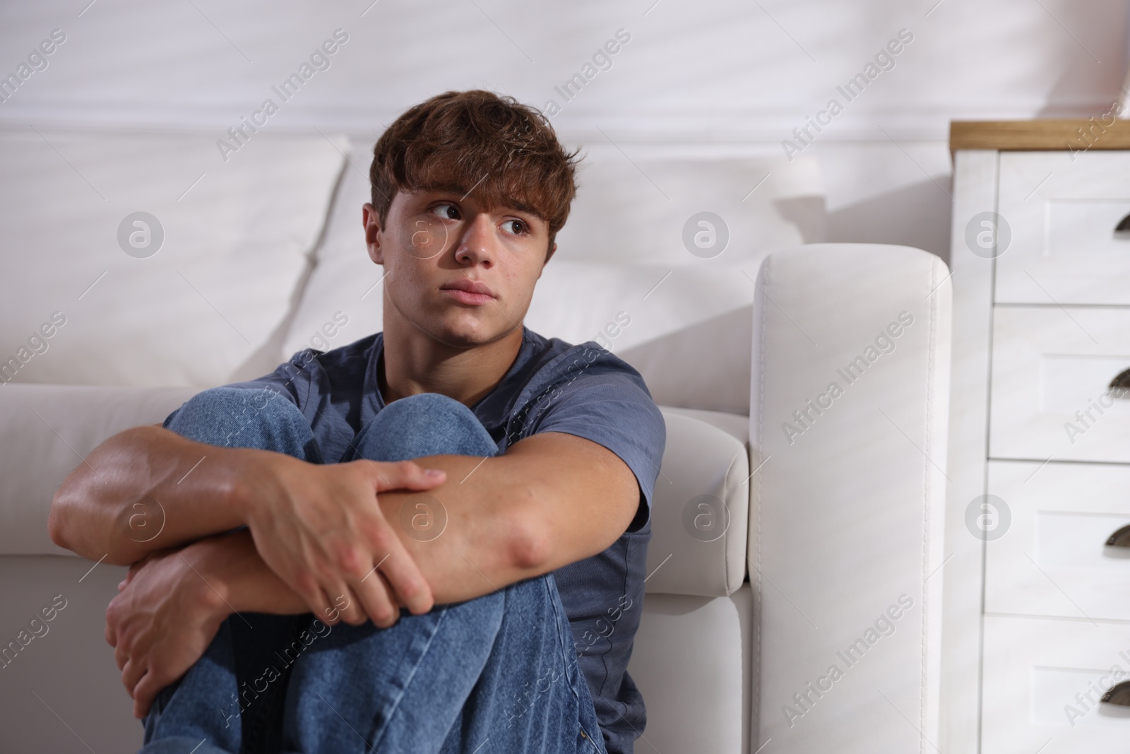 Photo of Teenage boy suffering from panic near sofa at home