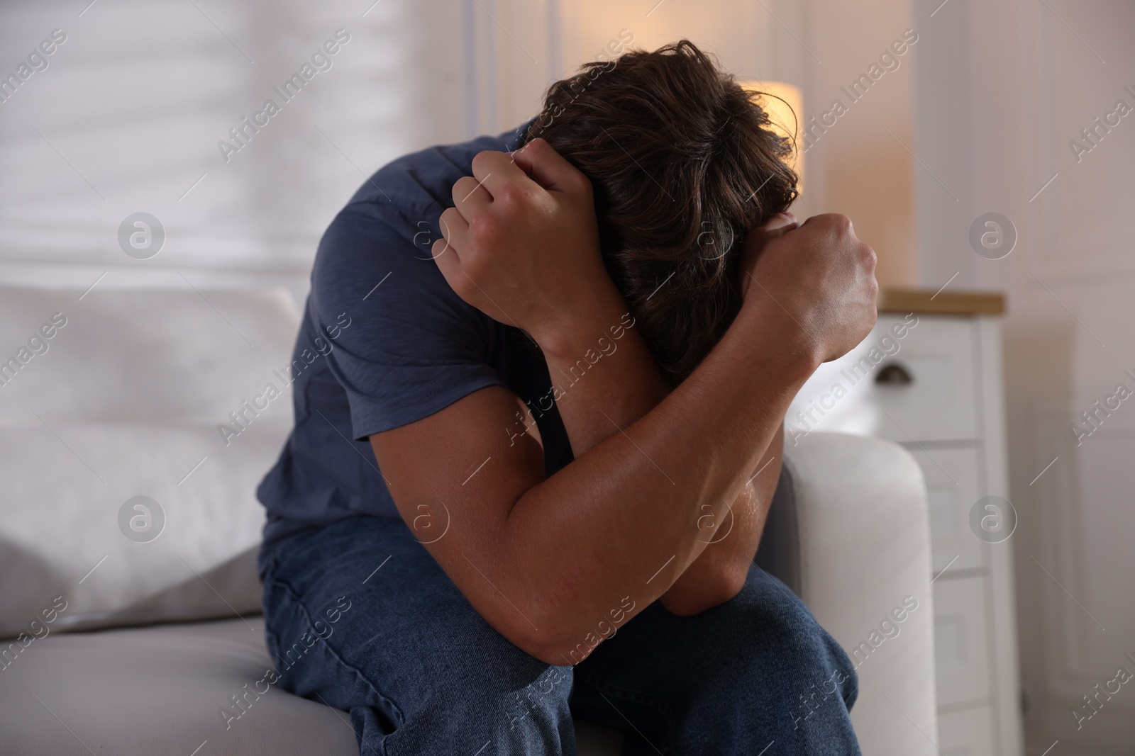 Photo of Teenage boy suffering from panic attack on sofa at home