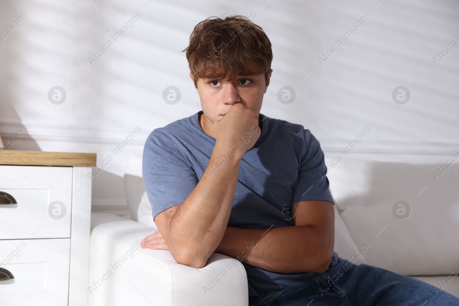 Photo of Teenage boy suffering from panic on sofa at home