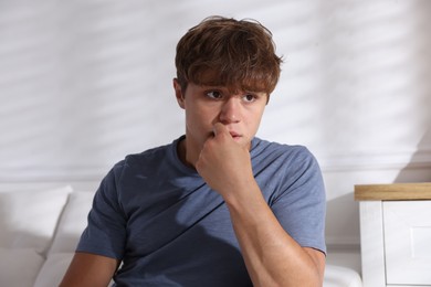 Photo of Teenage boy suffering from panic on sofa at home