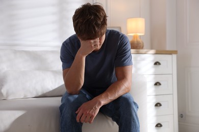 Photo of Teenage boy suffering from panic attack on sofa at home