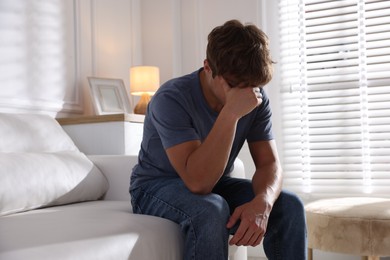 Photo of Teenage boy suffering from panic attack on sofa at home
