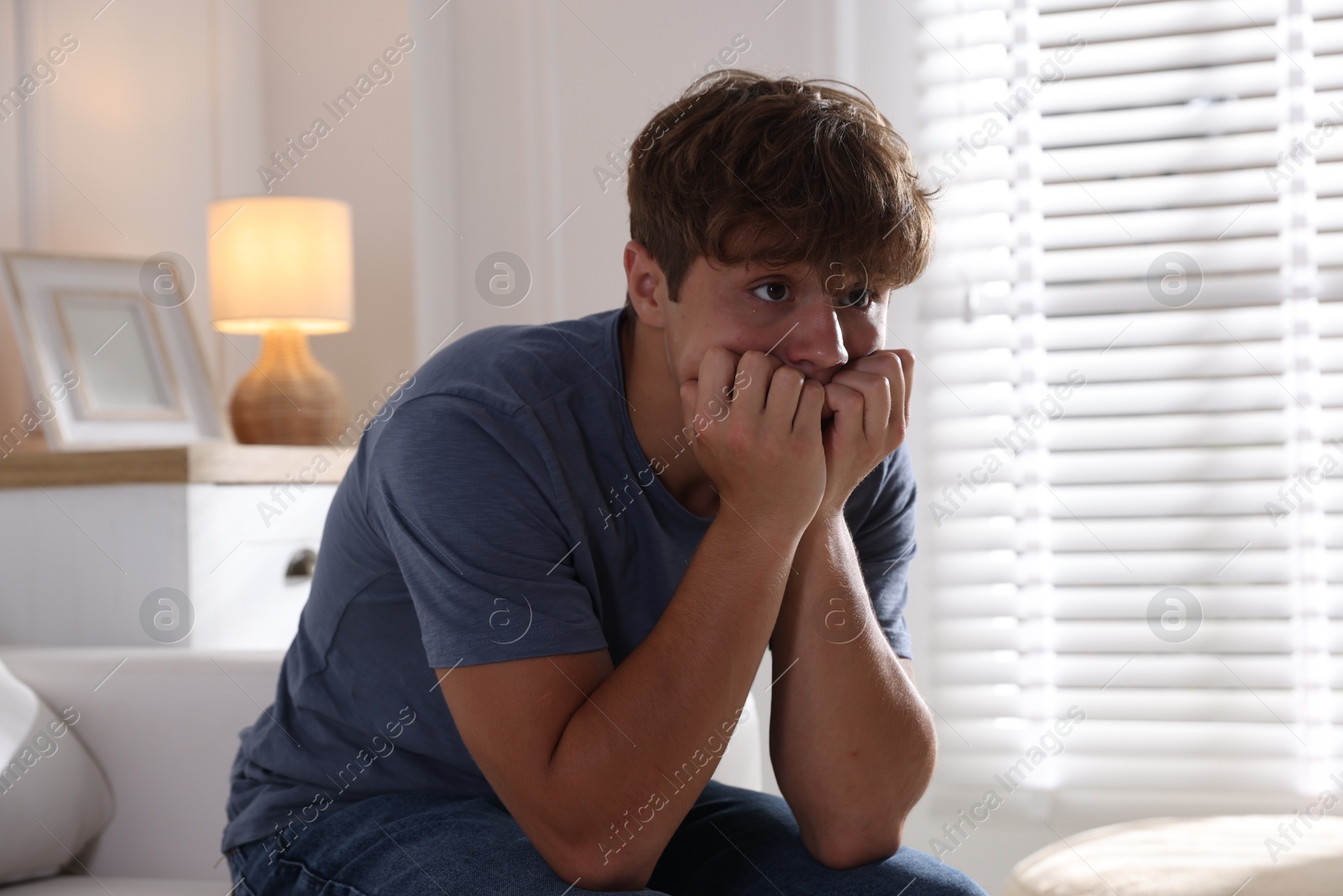 Photo of Teenage boy suffering from panic attack on sofa at home