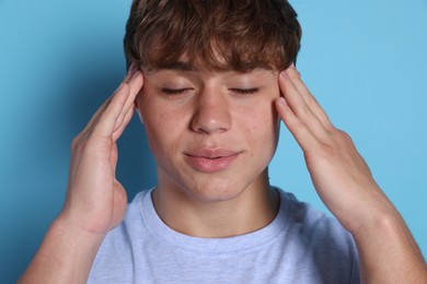 Photo of Teenage boy meditating on light blue background. Way to stop panic attack
