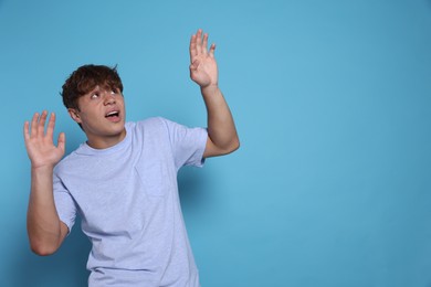 Photo of Teenage boy suffering from panic attack on light blue background. Space for text