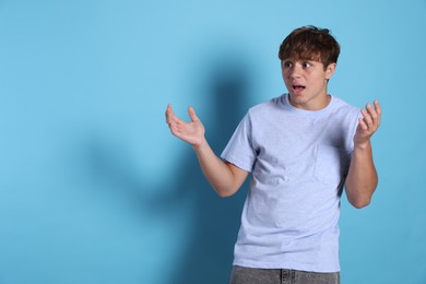 Photo of Teenage boy suffering from panic attack on light blue background. Space for text