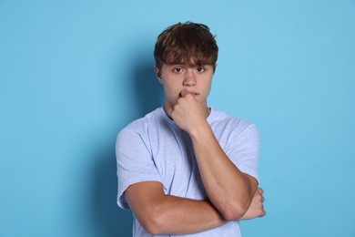 Photo of Teenage boy suffering from panic attack on light blue background