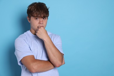 Photo of Teenage boy suffering from panic attack on light blue background. Space for text
