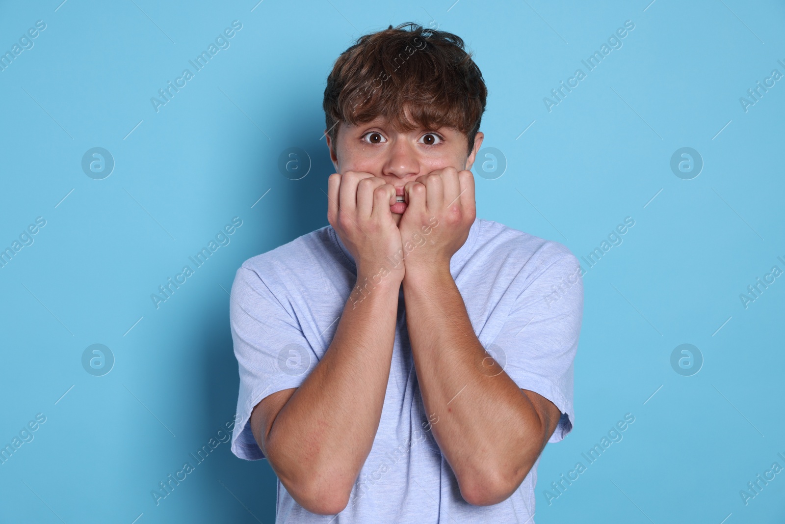 Photo of Teenage boy suffering from panic attack on light blue background