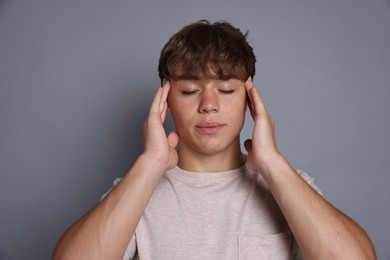 Photo of Teenage boy meditating on grey background. Way to stop panic attack