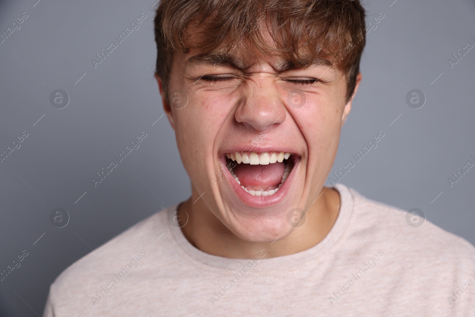 Photo of Teenage boy suffering from panic attack on grey background
