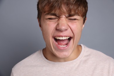 Photo of Teenage boy suffering from panic attack on grey background