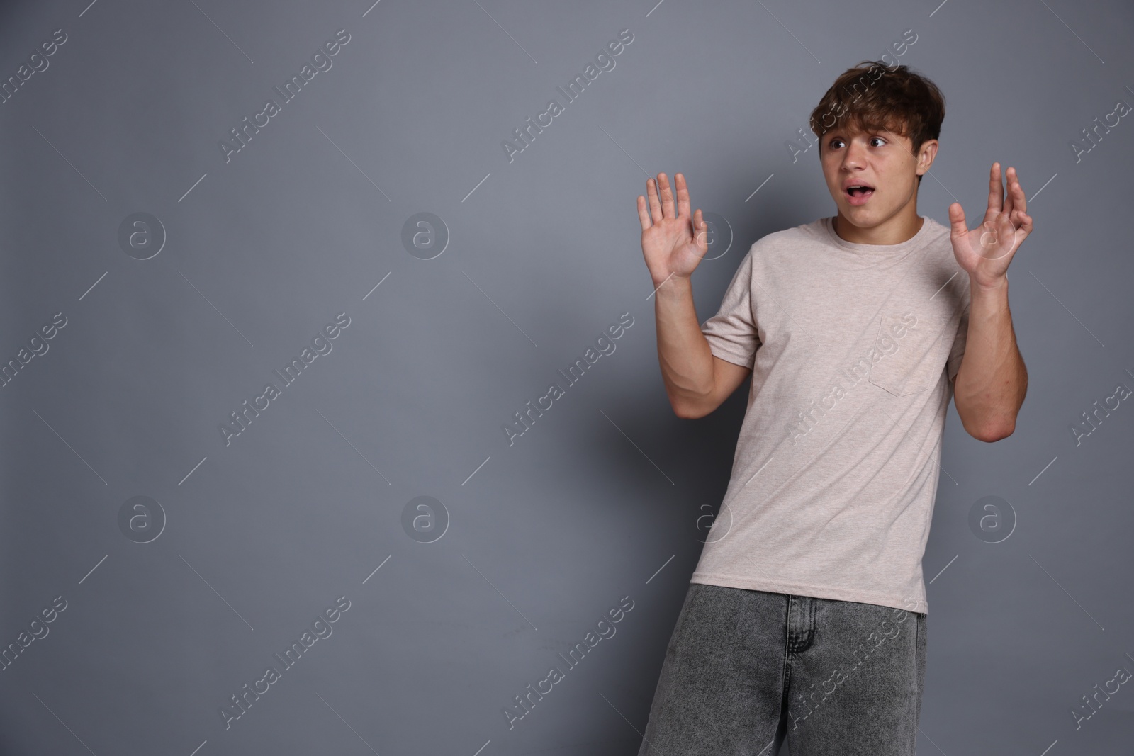 Photo of Teenage boy suffering from panic attack on grey background. Space for text
