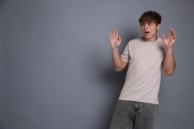 Photo of Teenage boy suffering from panic attack on grey background. Space for text