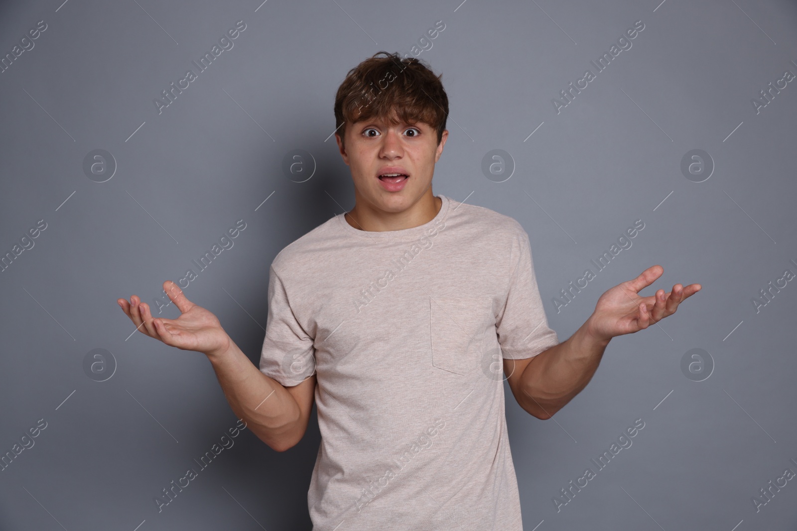 Photo of Teenage boy suffering from panic attack on grey background