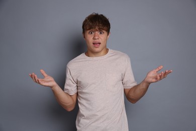 Photo of Teenage boy suffering from panic attack on grey background