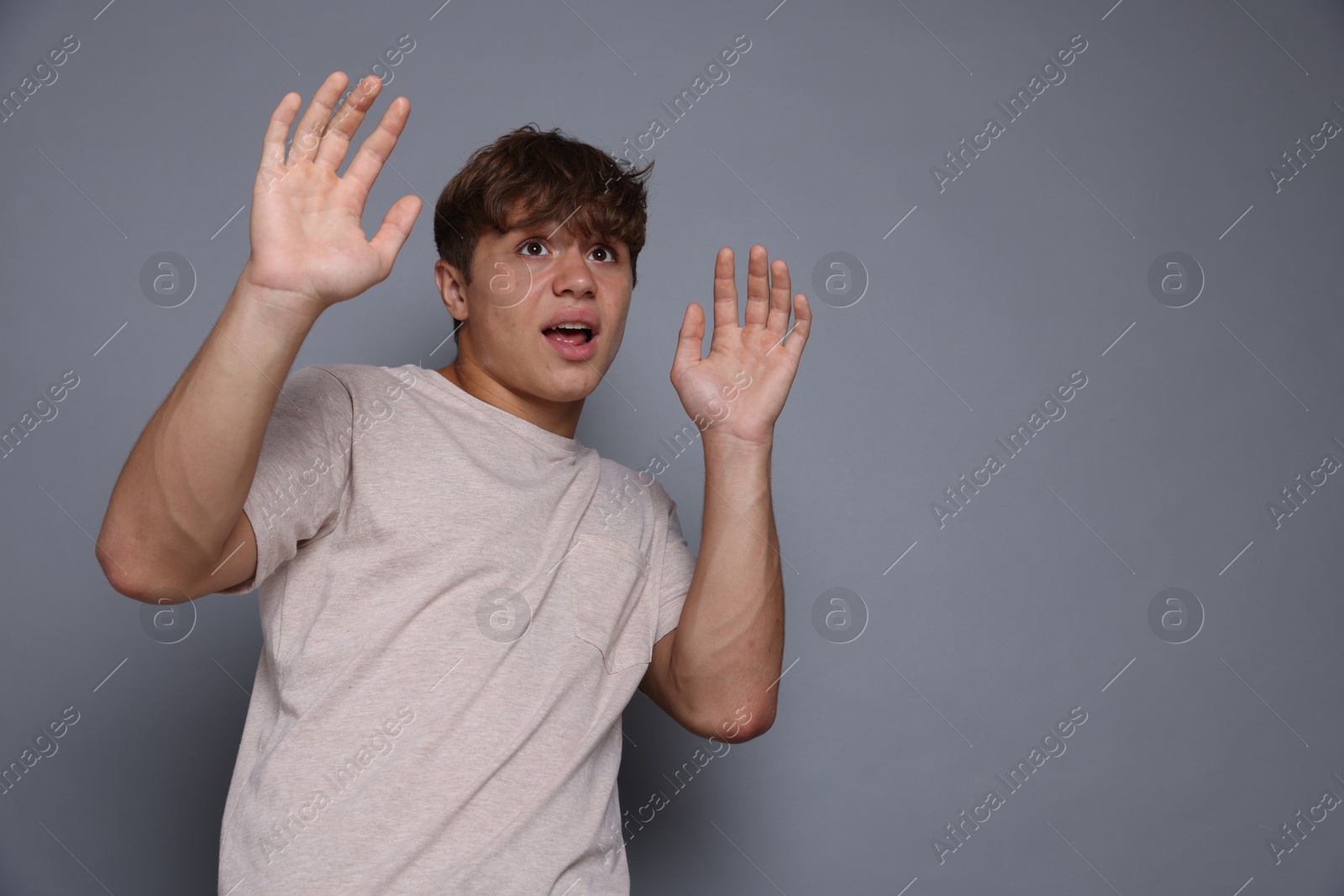 Photo of Teenage boy suffering from panic attack on grey background. Space for text
