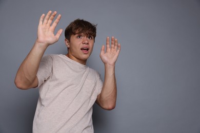 Photo of Teenage boy suffering from panic attack on grey background. Space for text