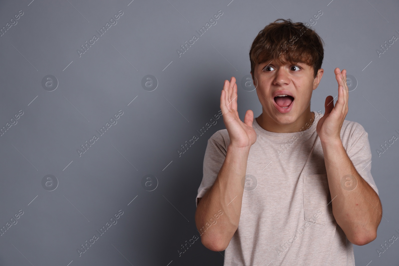 Photo of Teenage boy suffering from panic attack on grey background. Space for text
