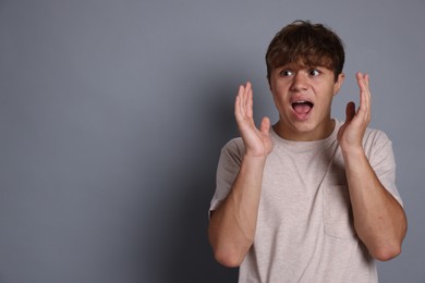 Photo of Teenage boy suffering from panic attack on grey background. Space for text