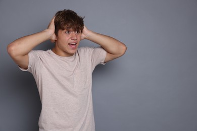 Photo of Teenage boy suffering from panic attack on grey background. Space for text