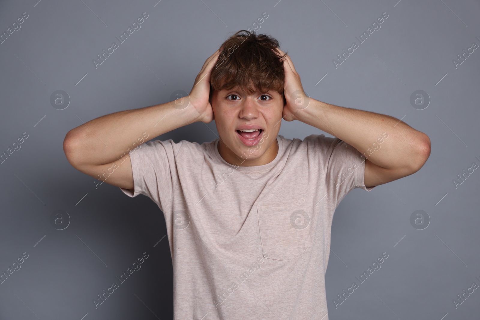 Photo of Teenage boy suffering from panic attack on grey background