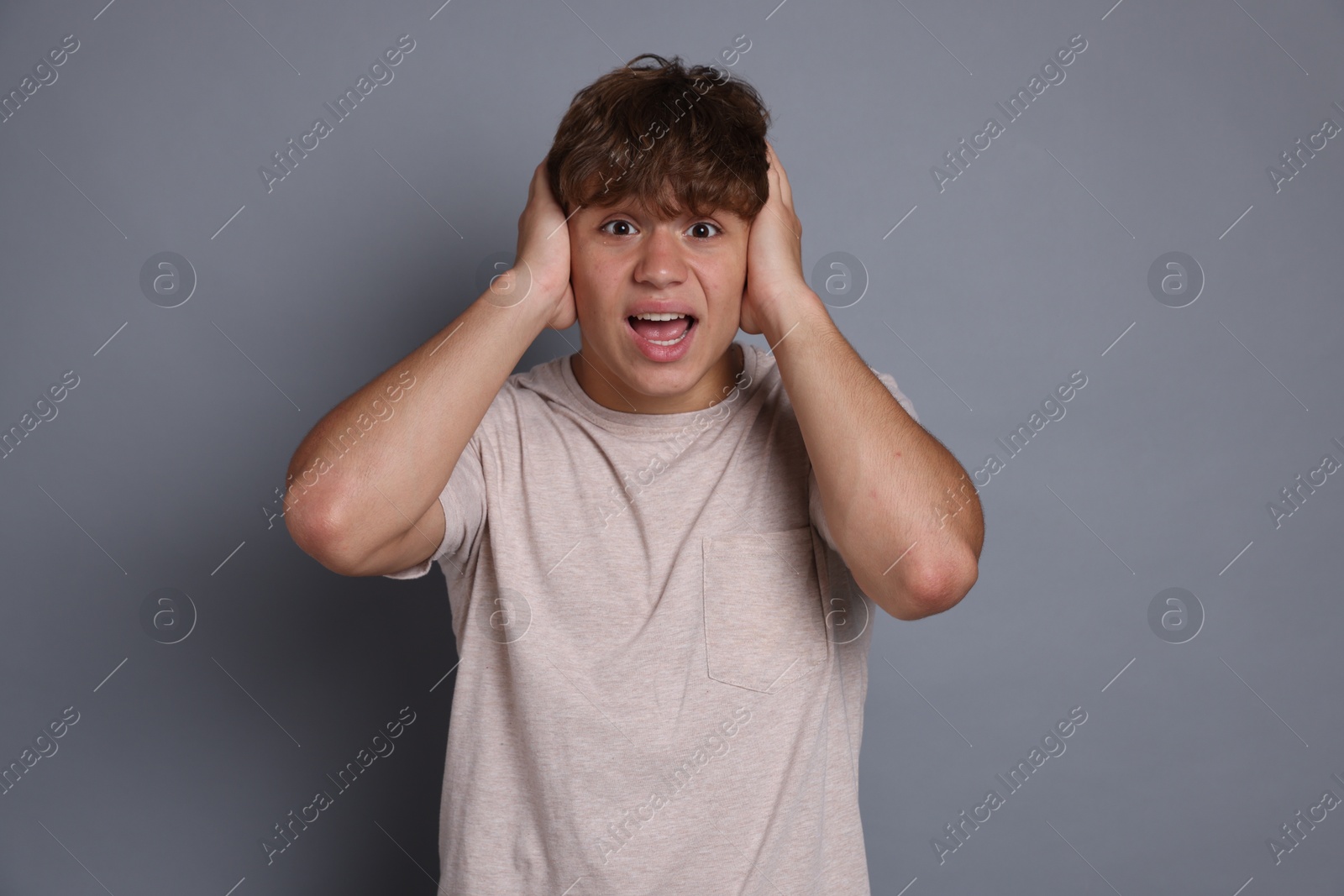 Photo of Teenage boy suffering from panic attack on grey background