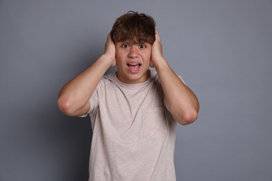 Photo of Teenage boy suffering from panic attack on grey background