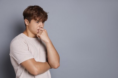 Photo of Teenage boy suffering from panic attack on grey background. Space for text