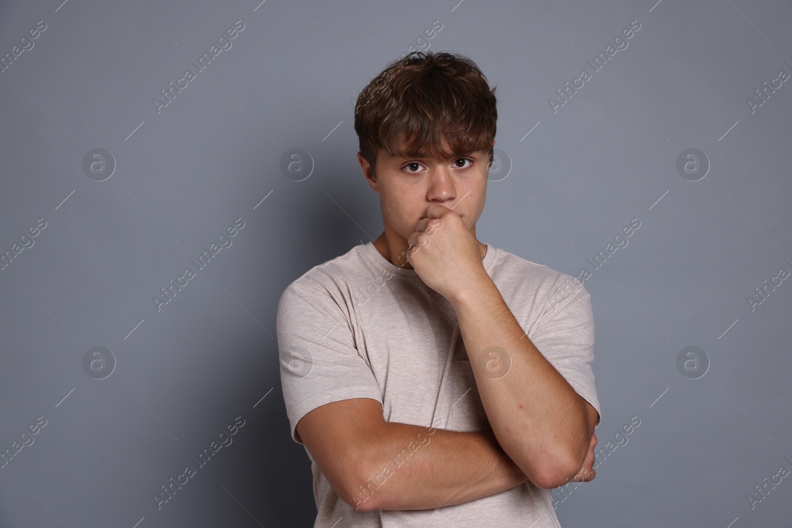 Photo of Teenage boy suffering from panic attack on grey background