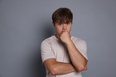 Photo of Teenage boy suffering from panic attack on grey background