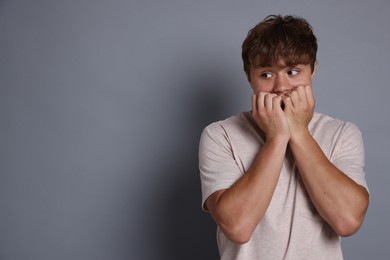 Photo of Teenage boy suffering from panic attack on grey background. Space for text