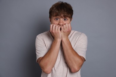 Photo of Teenage boy suffering from panic attack on grey background