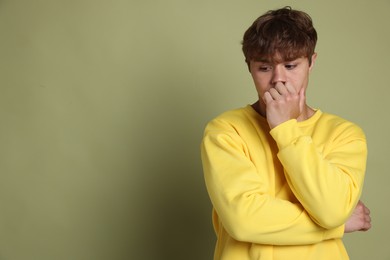 Photo of Teenage boy suffering from panic attack on green background. Space for text
