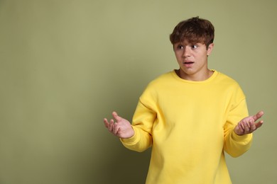 Photo of Teenage boy suffering from panic attack on green background. Space for text