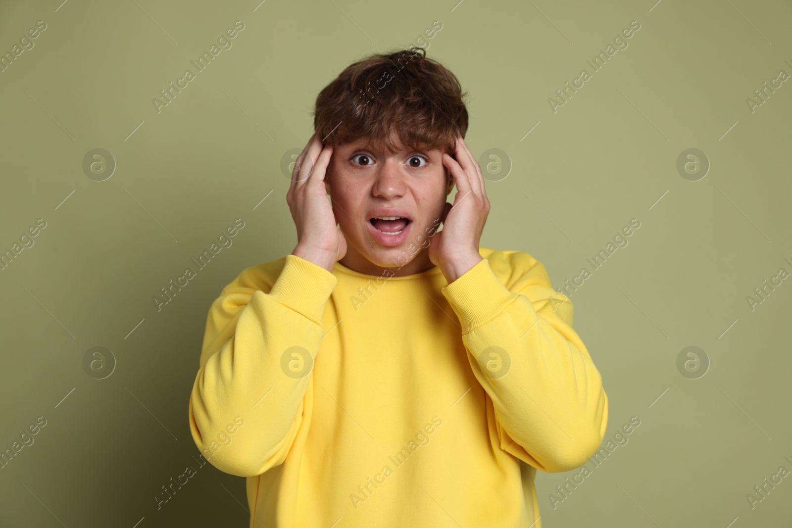 Photo of Teenage boy suffering from panic attack on green background