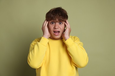 Photo of Teenage boy suffering from panic attack on green background