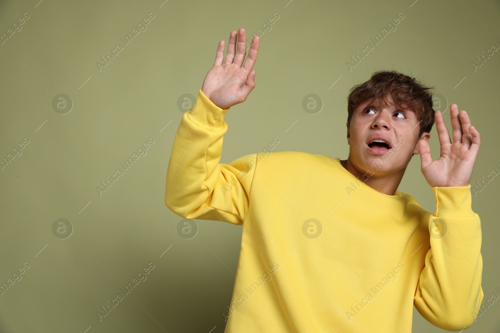 Photo of Teenage boy suffering from panic attack on green background. Space for text