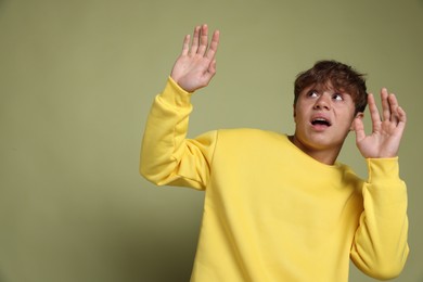Photo of Teenage boy suffering from panic attack on green background. Space for text