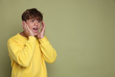 Photo of Teenage boy suffering from panic attack on green background. Space for text